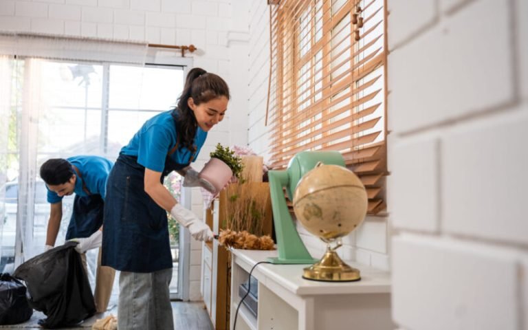 Asian young man and woman cleaning service worker work in living room. Attractive housekeeper cleaner team wear apron and cleaning messy dirty floor for housekeeping housework and chores in house.